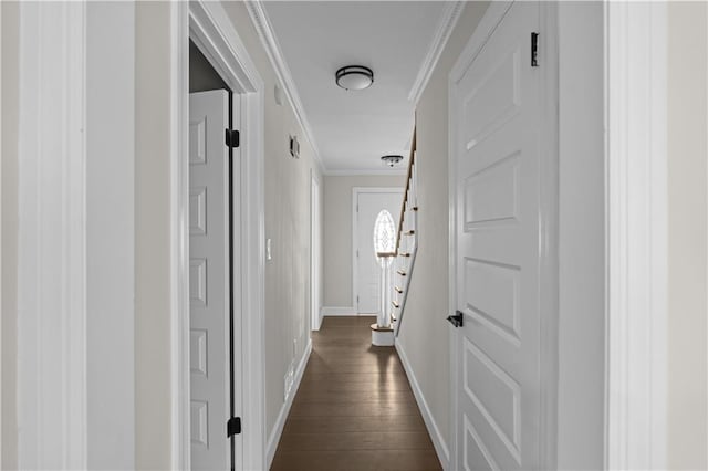 hallway with dark wood finished floors, crown molding, stairway, and baseboards