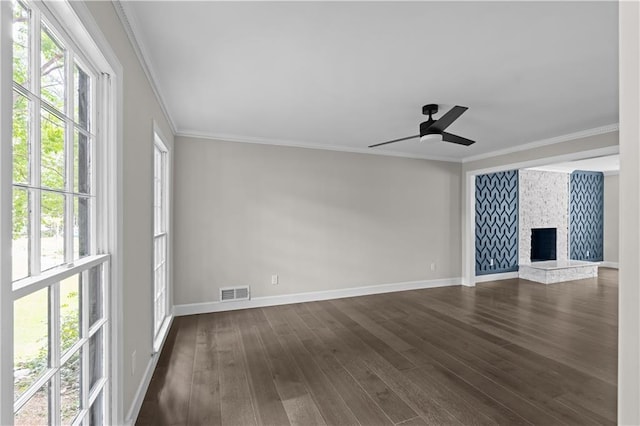 unfurnished living room featuring a wealth of natural light, a fireplace, dark wood-style flooring, and crown molding