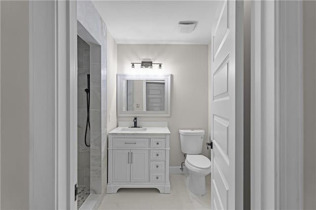 bathroom with toilet, baseboards, a tile shower, and vanity