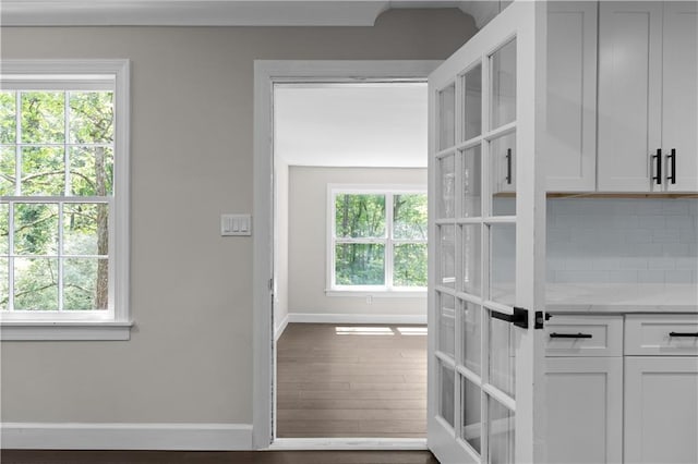 interior space with baseboards, backsplash, dark wood finished floors, and white cabinets