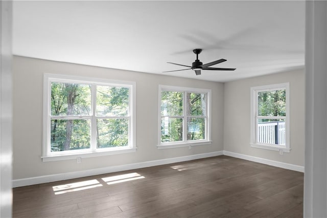 spare room featuring dark wood finished floors, a ceiling fan, and baseboards