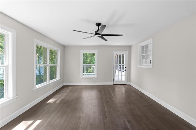 spare room with dark wood finished floors, a ceiling fan, and baseboards