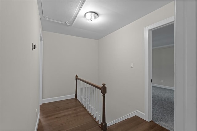 corridor with attic access, baseboards, dark wood-style flooring, and an upstairs landing