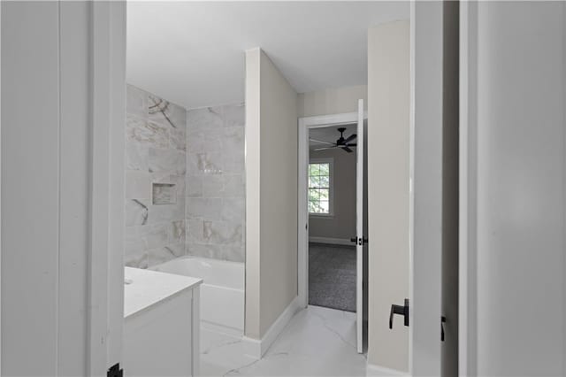 bathroom featuring marble finish floor, baseboards, shower / washtub combination, and vanity