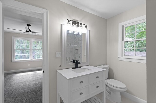 half bathroom with toilet, ceiling fan, baseboards, and vanity