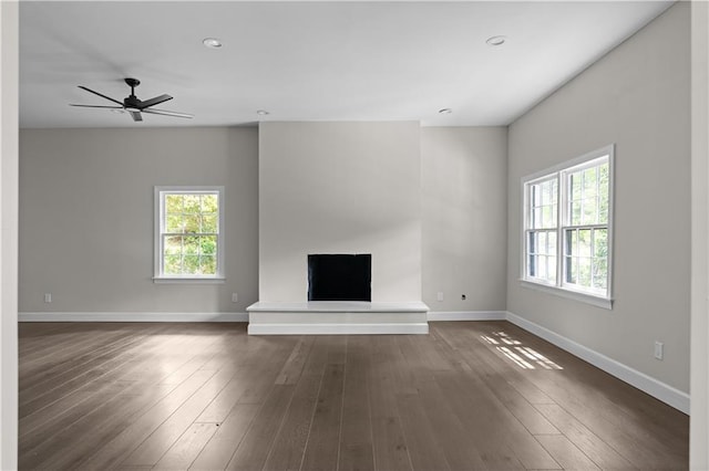 unfurnished living room with a healthy amount of sunlight, baseboards, and dark wood-type flooring