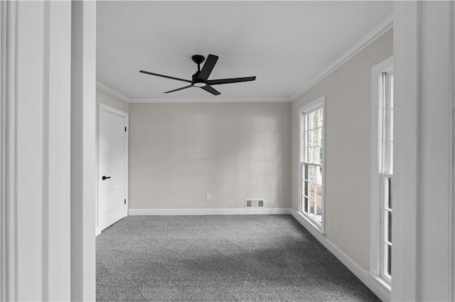 carpeted empty room with ornamental molding, a ceiling fan, visible vents, and baseboards