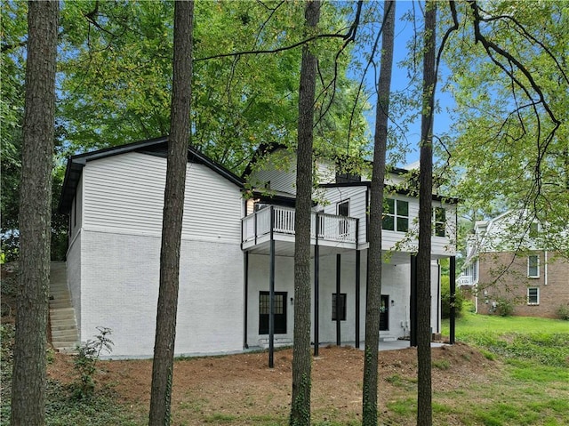 rear view of property with brick siding and a balcony