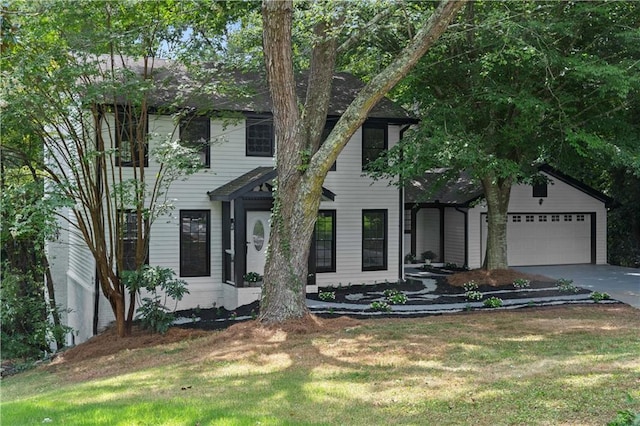 colonial house featuring a garage, driveway, and a front lawn