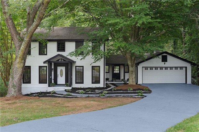 colonial-style house featuring an attached garage, concrete driveway, and a front yard