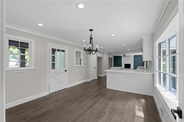 kitchen with light countertops, ornamental molding, open floor plan, white cabinetry, and a peninsula