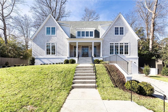 view of front of home with a porch, a front yard, fence, and stairs