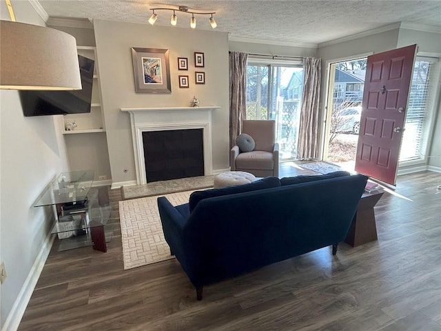 living room with a textured ceiling, a fireplace with raised hearth, ornamental molding, and dark wood-style flooring