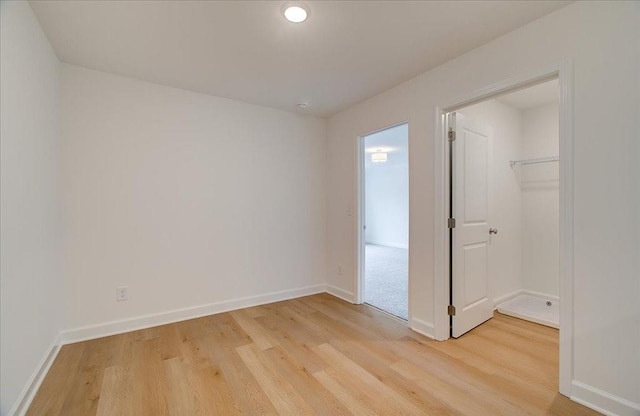 unfurnished bedroom featuring a walk in closet and light hardwood / wood-style flooring