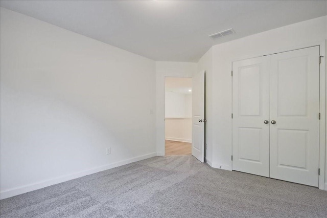 unfurnished bedroom with light colored carpet and a closet