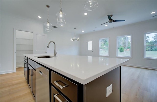 kitchen featuring sink, dishwasher, an island with sink, decorative light fixtures, and light wood-type flooring