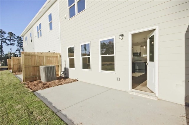 back of property with cooling unit, a yard, and a patio area