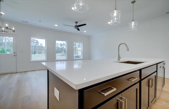 kitchen featuring pendant lighting, sink, a center island with sink, and light hardwood / wood-style floors