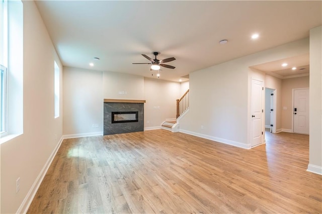 138 Henley St, Canton, GA 30114 - unfurnished living room with ceiling fan, light wood-type flooring, stairway, a tiled fireplace, and baseboards