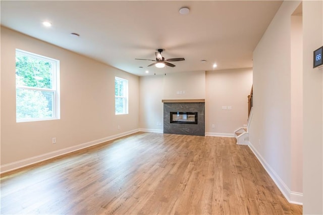138 Henley St, Canton, GA 30114 - unfurnished living room featuring light wood finished floors, a glass covered fireplace, a ceiling fan, stairs, and baseboards