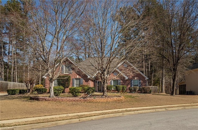 view of front of property featuring brick siding, fence, and a front lawn