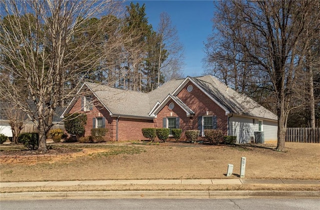 view of front of home with brick siding, central AC, and fence