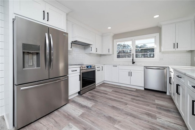 kitchen with a sink, decorative backsplash, white cabinets, and stainless steel appliances