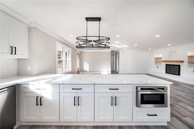 kitchen with appliances with stainless steel finishes, light stone counters, white cabinetry, open floor plan, and recessed lighting