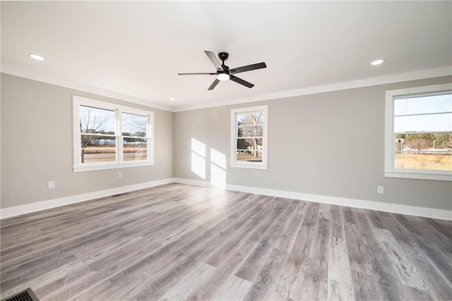 spare room with crown molding, a ceiling fan, wood finished floors, and a healthy amount of sunlight