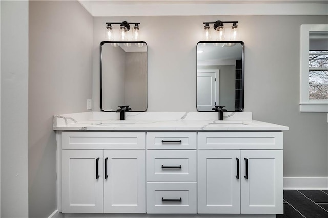 full bathroom with baseboards, a sink, and double vanity