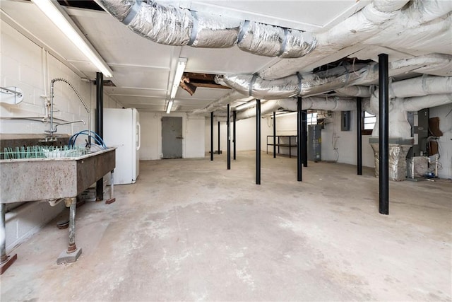 unfinished below grade area featuring freestanding refrigerator, a sink, water heater, and electric panel