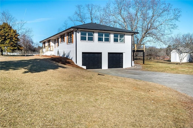 view of side of home featuring a garage, stucco siding, a yard, and aphalt driveway