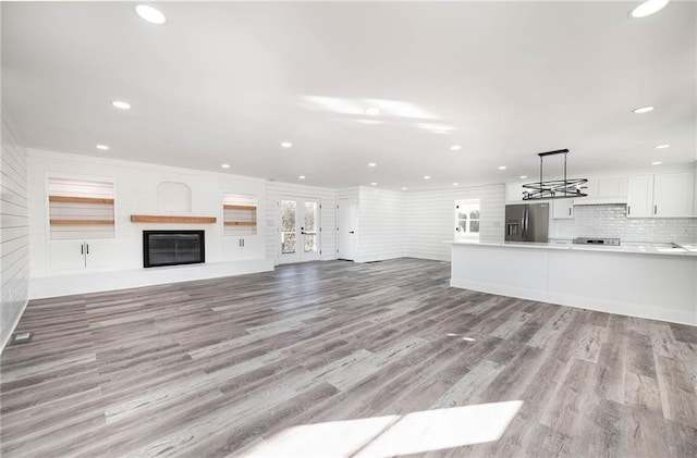 unfurnished living room featuring a glass covered fireplace, recessed lighting, and light wood-style flooring
