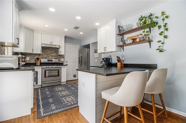 1175 Haven Brook Way, Atlanta, GA 30319 - kitchen with appliances with stainless steel finishes, a peninsula, dark countertops, under cabinet range hood, and white cabinetry