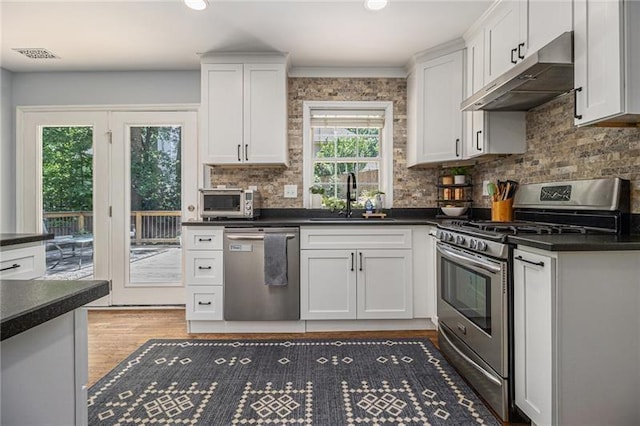 1175 Haven Brook Way, Atlanta, GA 30319 - kitchen featuring appliances with stainless steel finishes, under cabinet range hood, dark countertops, white cabinetry, and tasteful backsplash