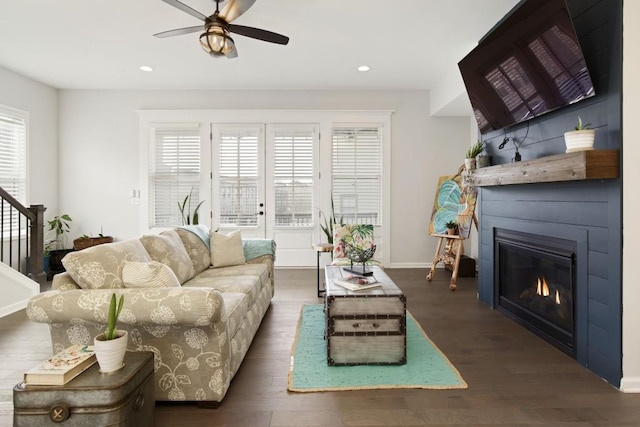 living room with ceiling fan, a fireplace, and dark hardwood / wood-style floors