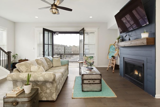 living room featuring dark hardwood / wood-style flooring, a large fireplace, and ceiling fan