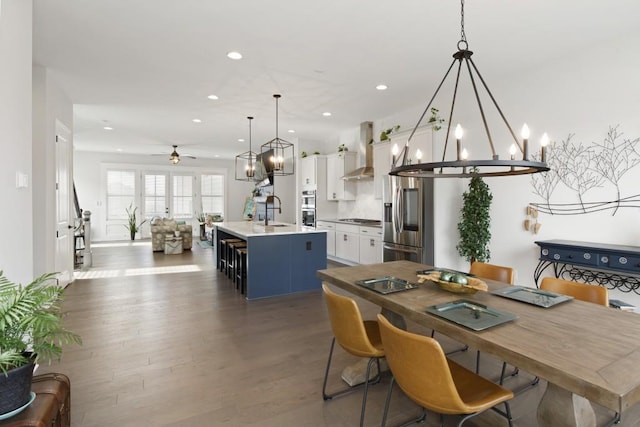 dining area featuring sink, dark wood-type flooring, and ceiling fan with notable chandelier