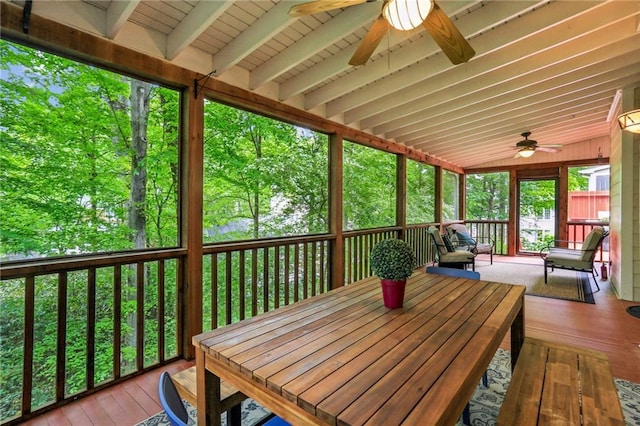 sunroom with beam ceiling, a ceiling fan, and outdoor dining area