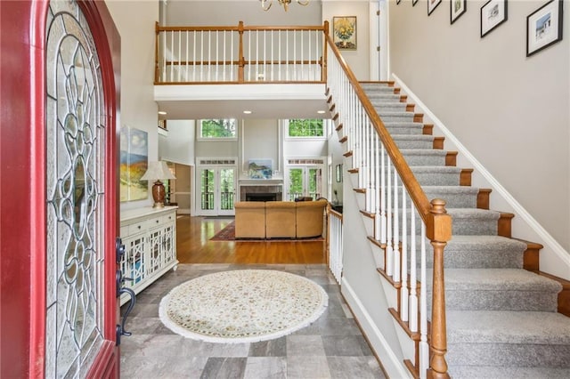 foyer entrance with baseboards, stairs, a fireplace, and a towering ceiling
