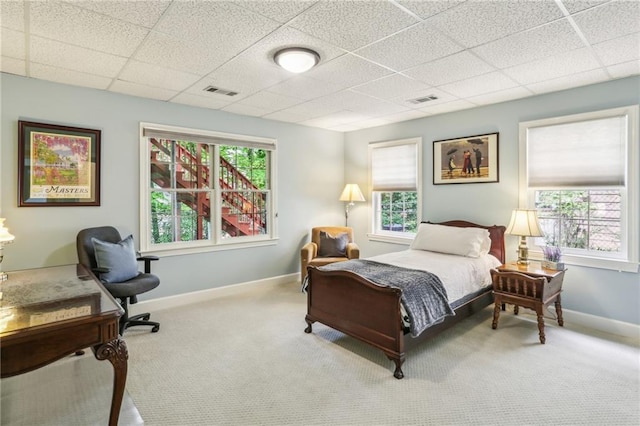 carpeted bedroom with a paneled ceiling, visible vents, and baseboards
