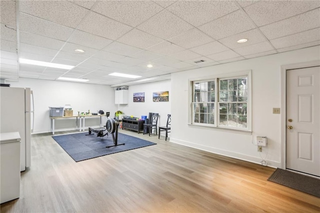 exercise room with recessed lighting, a paneled ceiling, wood finished floors, and baseboards