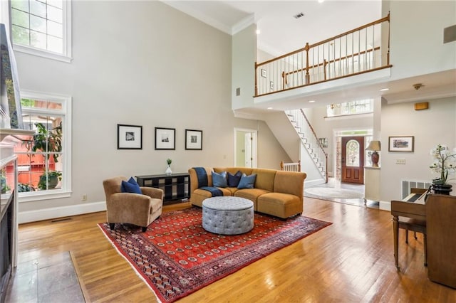 living area with baseboards, a wealth of natural light, stairs, and a towering ceiling