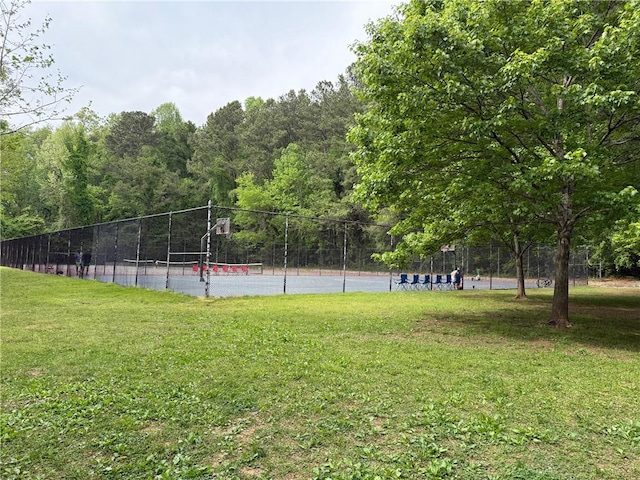 view of property's community with a tennis court, a yard, and fence