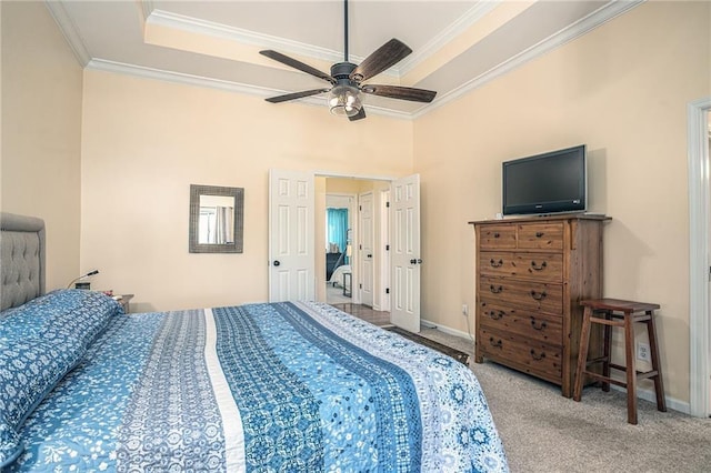 bedroom featuring ornamental molding, baseboards, a tray ceiling, and carpet floors