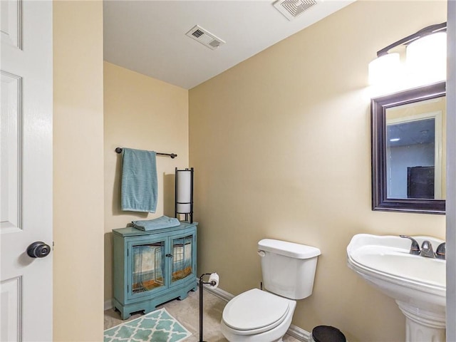 half bath featuring tile patterned floors, toilet, baseboards, and visible vents