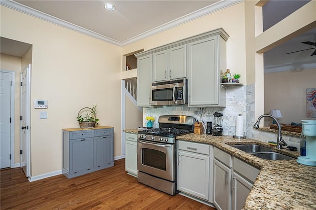 kitchen with ornamental molding, a sink, tasteful backsplash, stainless steel appliances, and light wood-style floors