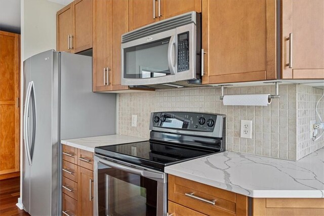 855 Peachtree St NE Unit 2713, Atlanta, GA 30308 - kitchen featuring decorative backsplash, brown cabinets, light stone countertops, and stainless steel appliances