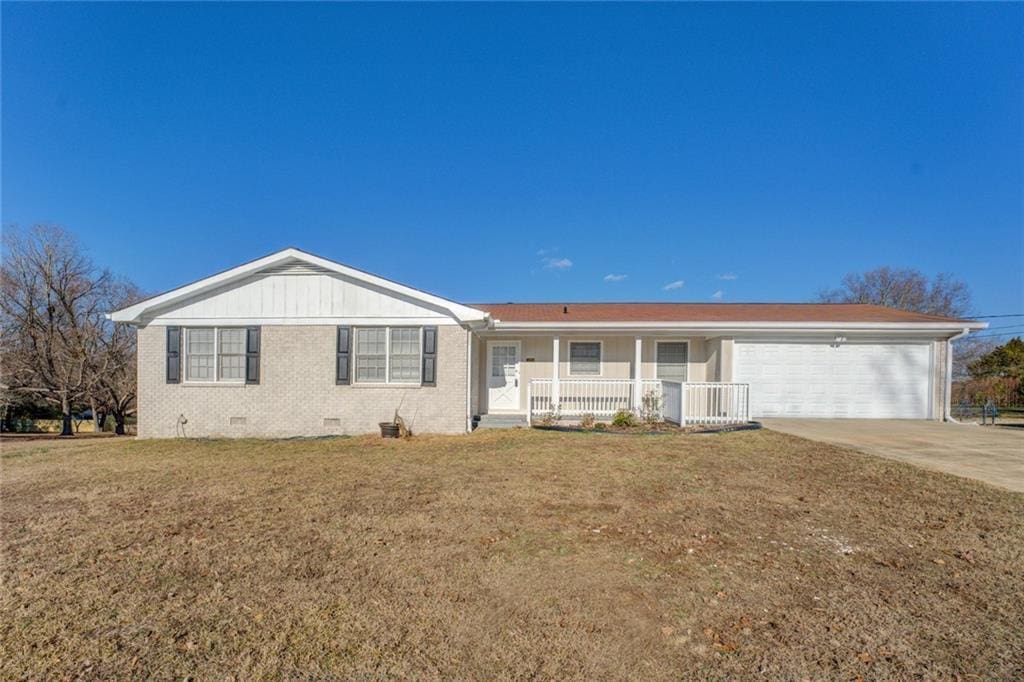 ranch-style home with a front lawn, covered porch, and a garage