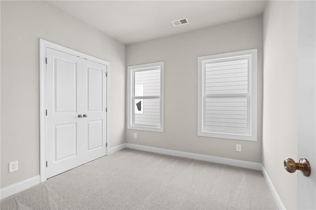 unfurnished bedroom with light carpet and a closet